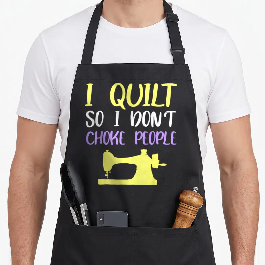 Choke quilt apron - I QUILT SO I DON'T CHOKE PEOPLE text in yellow white purple above sewing machine silhouette — shown on a black cotton canvas apron against a white background