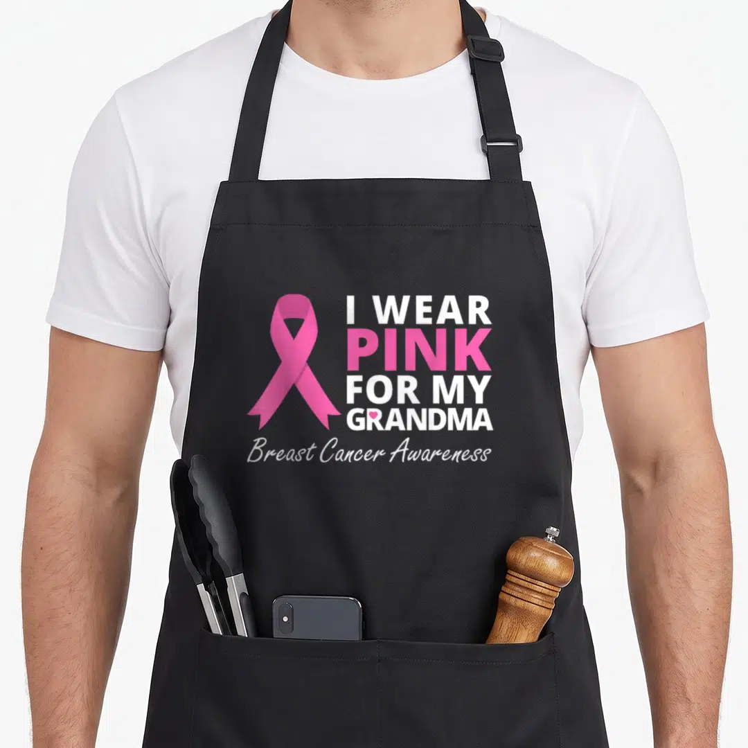Ribbon grandma apron - Pink awareness ribbon next to stacked text reading I Wear Pink For My Grandma Breast Cancer — shown on a black cotton canvas apron against a white background