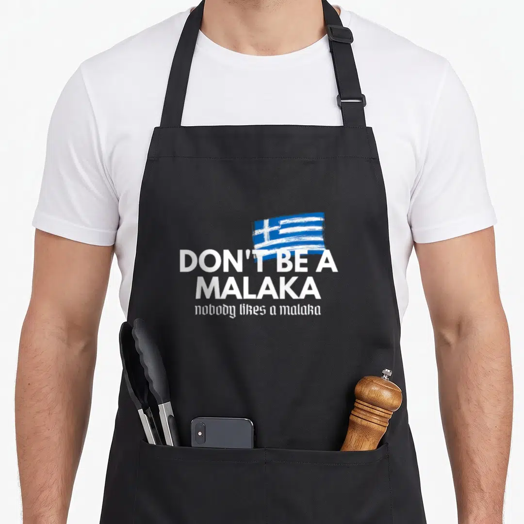 Malaka medusa greek aprons - White text reading Don't Be A Malaka below a blue and white brushstroke Greek flag — shown on a black cotton canvas apron against a white background