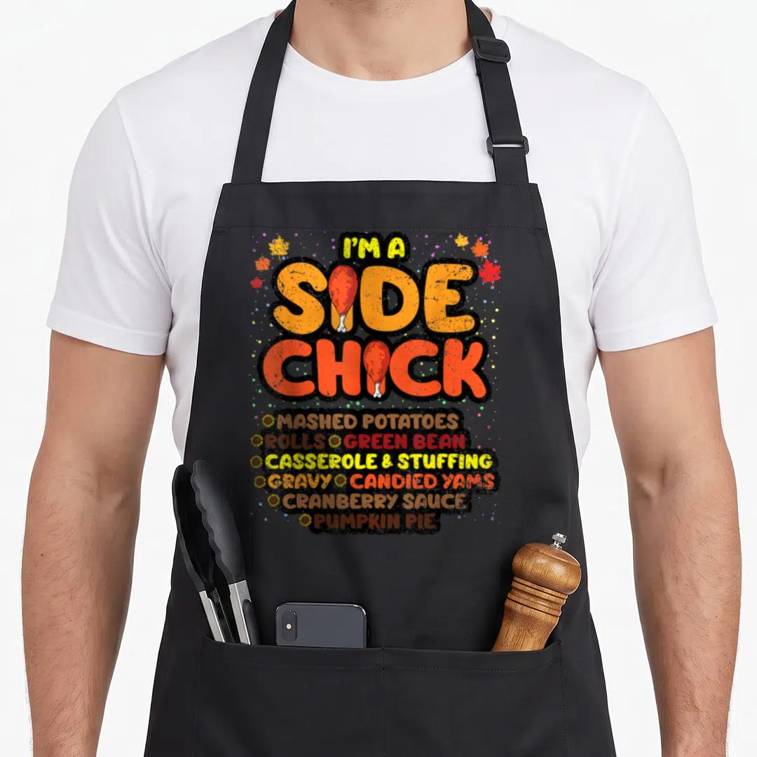 Chick thanksgiving day aprons - Side chick text with drumsticks and side dish list framed by sunflowers on black — shown on a black cotton canvas apron against a white background