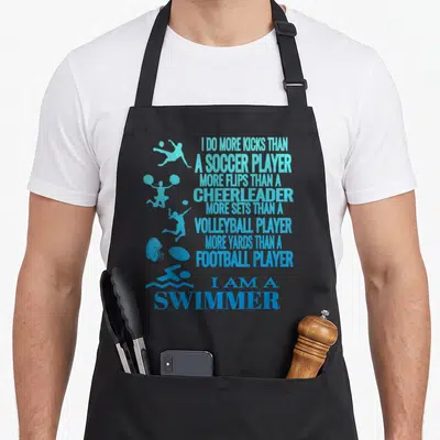 Swimmer i love swimming apron - Blue typography listing athletic comparisons between swimmers and other sports players — shown on a black cotton canvas apron against a white background