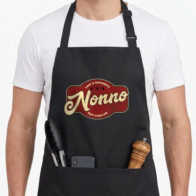 Grandpa italian apron - Red distressed badge with cream Nonno text and three stars — shown on a black cotton canvas apron against a white background