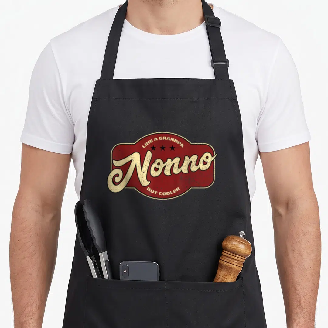 Grandpa italian apron - Red distressed badge with cream Nonno text and three stars — shown on a black cotton canvas apron against a white background