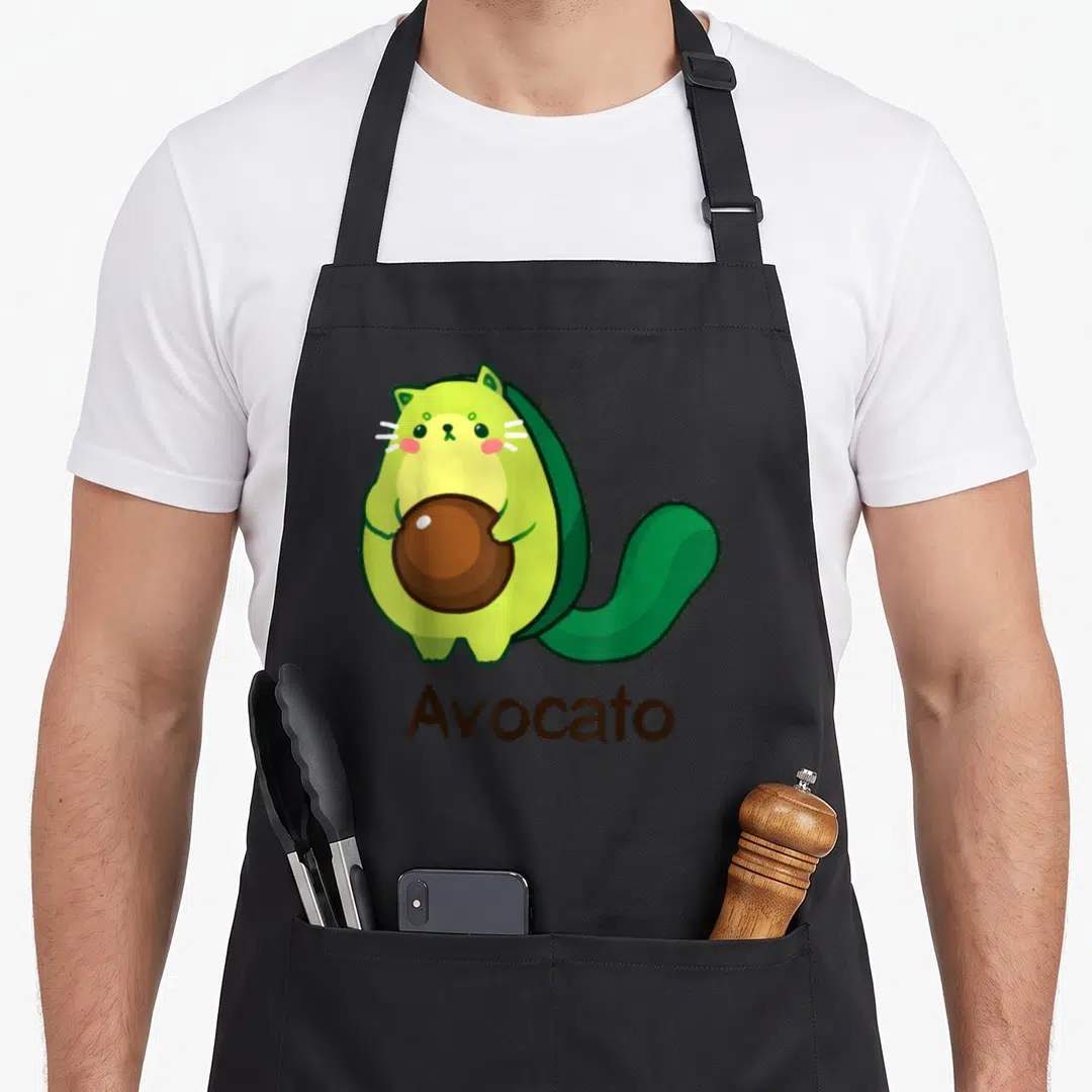 Avocato kitty cat apron - Cartoon avocado cat holding brown pit with Avocato text below — shown on a black cotton canvas apron against a white background
