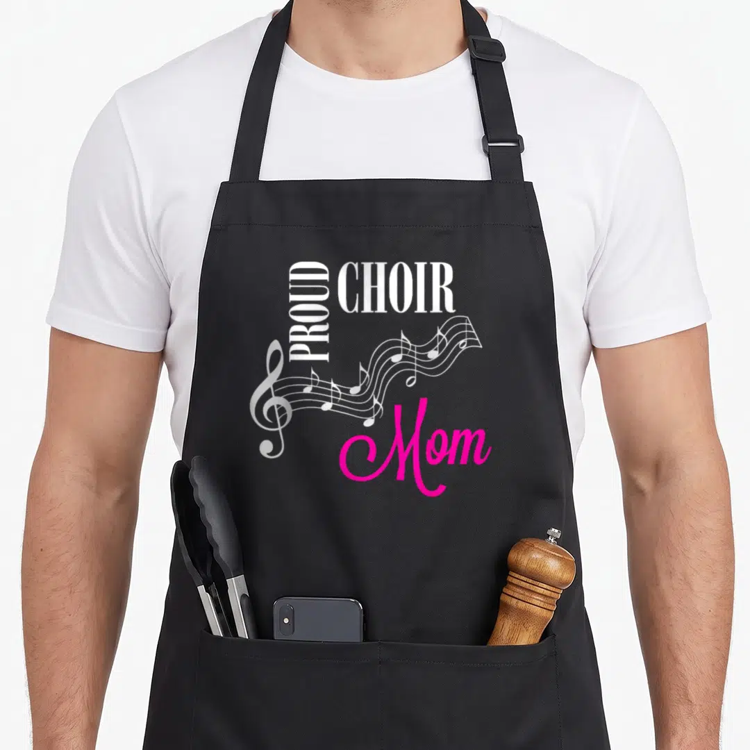 Choir mother's apron - Vertical PROUD text, horizontal CHOIR, pink Mom script, and white musical staff with treble clef — shown on a black cotton canvas apron against a white background