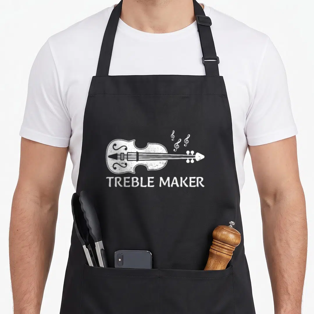 Violin viola apron - White line-art violin with three treble clefs and TREBLE MAKER text below — shown on a black cotton canvas apron against a white background