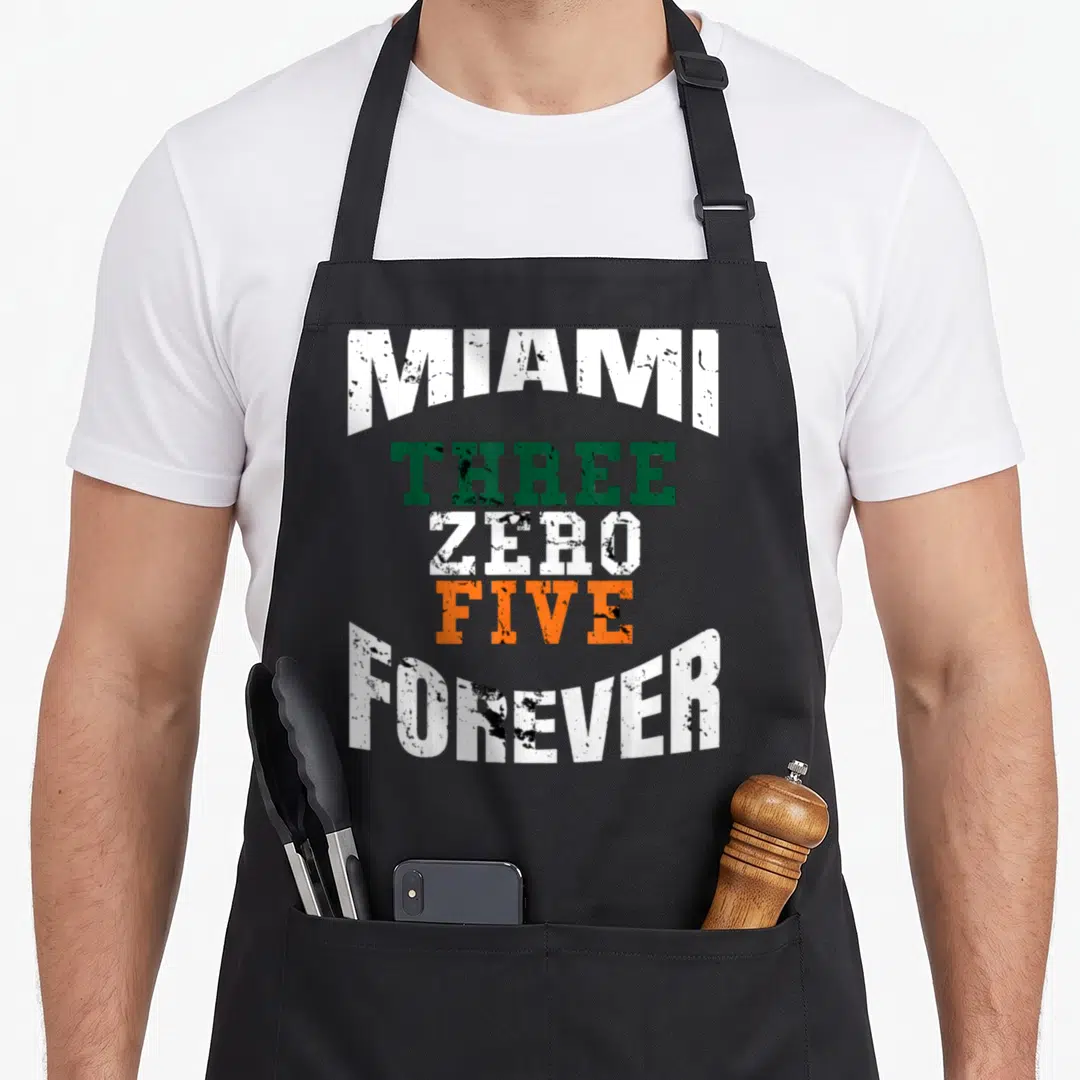 Area zero girl apron - Stacked MIAMI THREE ZERO FIVE FOREVER text in white green and orange distressed font — shown on a black cotton canvas apron against a white background