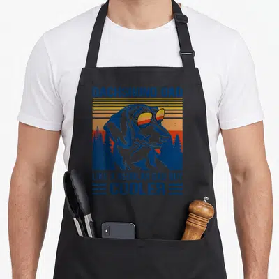 Dachshund father day apron - Retro dachshund wearing sunglasses in front of blue yellow orange red sunset and forest — shown on a black cotton canvas apron against a white background