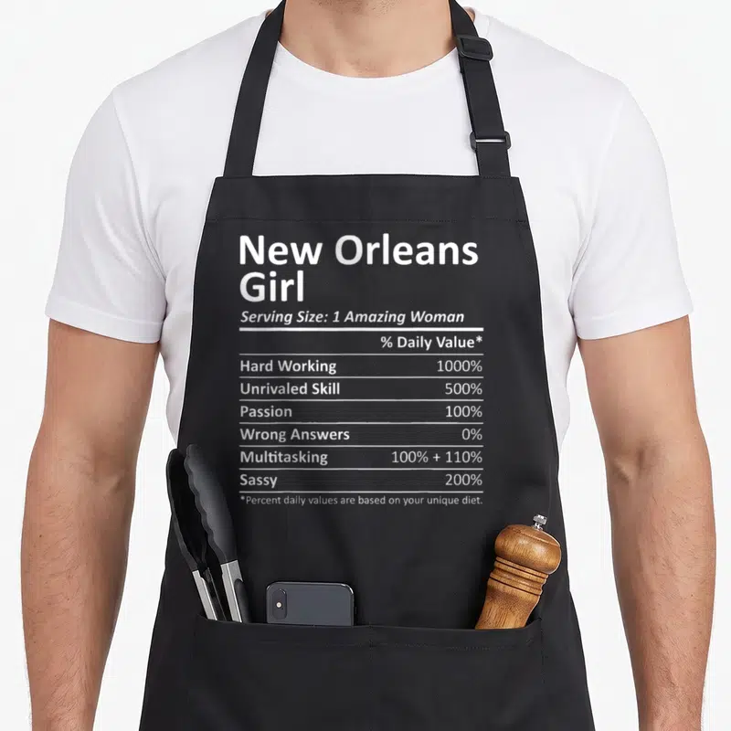 Orlean root louisiana apron - White nutrition label typography listing 1000% hard working and 200% sassy percentages — shown on a black cotton canvas apron against a white background
