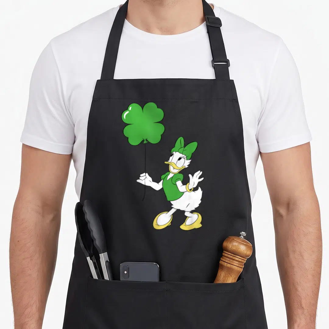 Leaf daisy apron - Cartoon Daisy Duck holding green four-leaf clover balloon wearing green outfit and yellow shoes — shown on a black cotton canvas apron against a white background