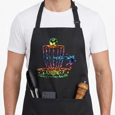 Golfing basket golf apron - Cartoon multicolored disc golf basket with perched disc and jumping figure in purple green — shown on a black cotton canvas apron against a white background