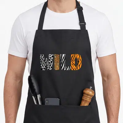 Pattern zebra apron - WILD text filled with cow, leopard, zebra, and tiger animal print patterns — shown on a black cotton canvas apron against a white background