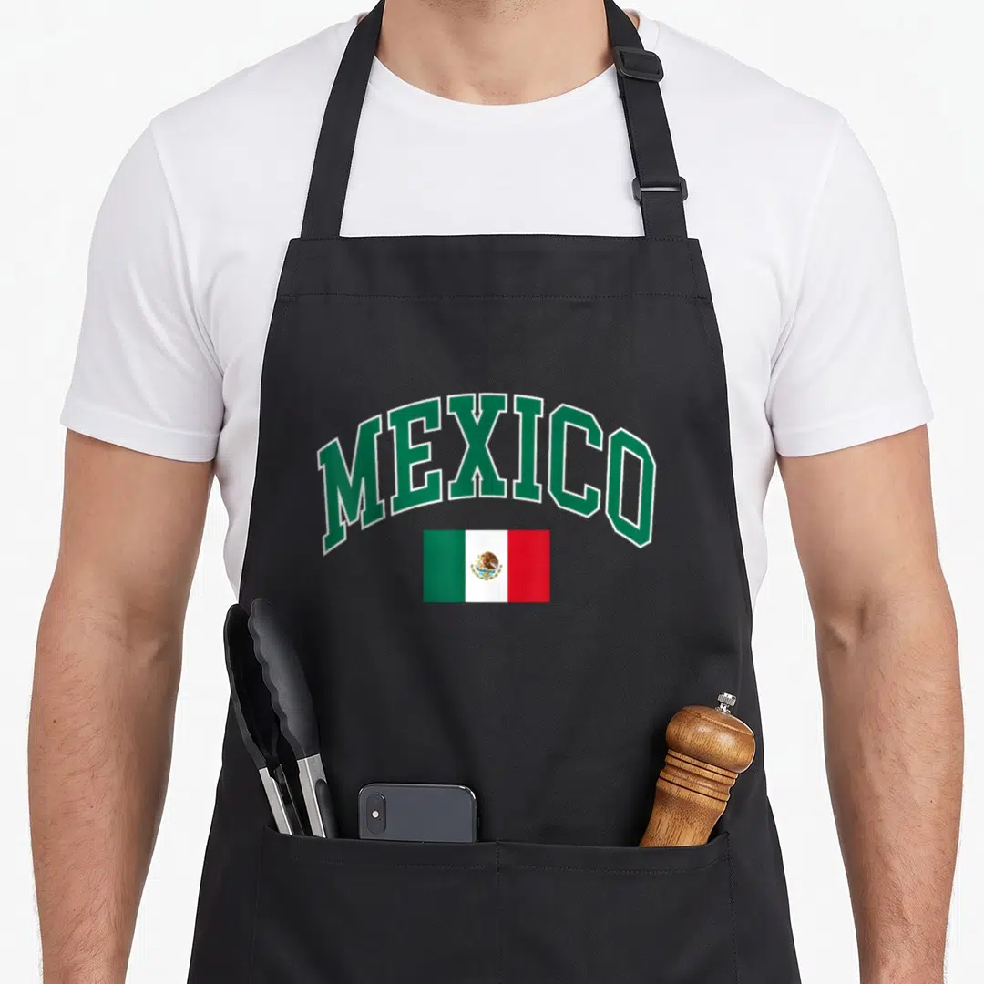 Funny mexican mexico apron - Arched green MEXICO text above small rectangular green white red flag — shown on a black cotton canvas apron against a white background