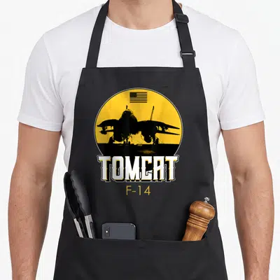 Tomcat air force veteran apron - Black F-14 jet silhouette in yellow circle with USA flag and white TOMCAT text — shown on a black cotton canvas apron against a white background