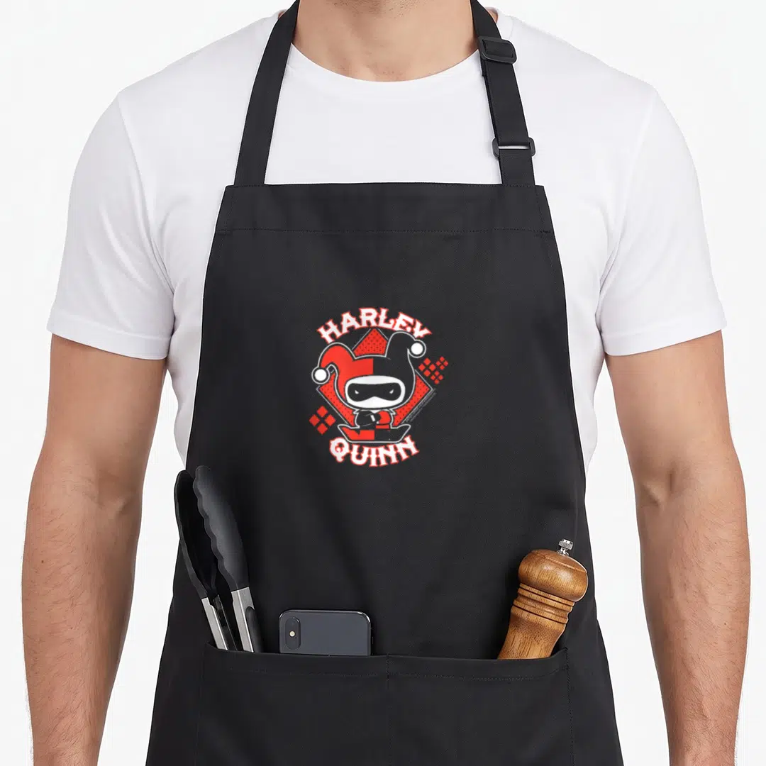 Funny chibi vehicle apron - Harley Quinn cartoon figure with red white geometric background and arched text — shown on a black cotton canvas apron against a white background