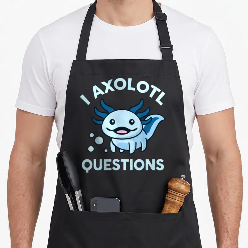 Axolotl questions apron for women - Cartoon light blue axolotl with pink tongue and bubbles beneath arching text — shown on a black cotton canvas apron against a white background