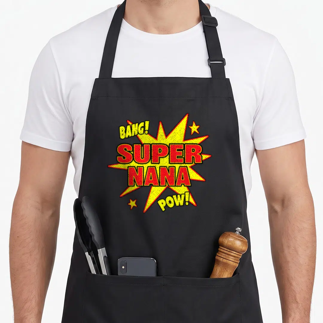 Power nana aprons - Yellow comic burst with red SUPER NANA text and BANG POW stars — shown on a black cotton canvas apron against a white background