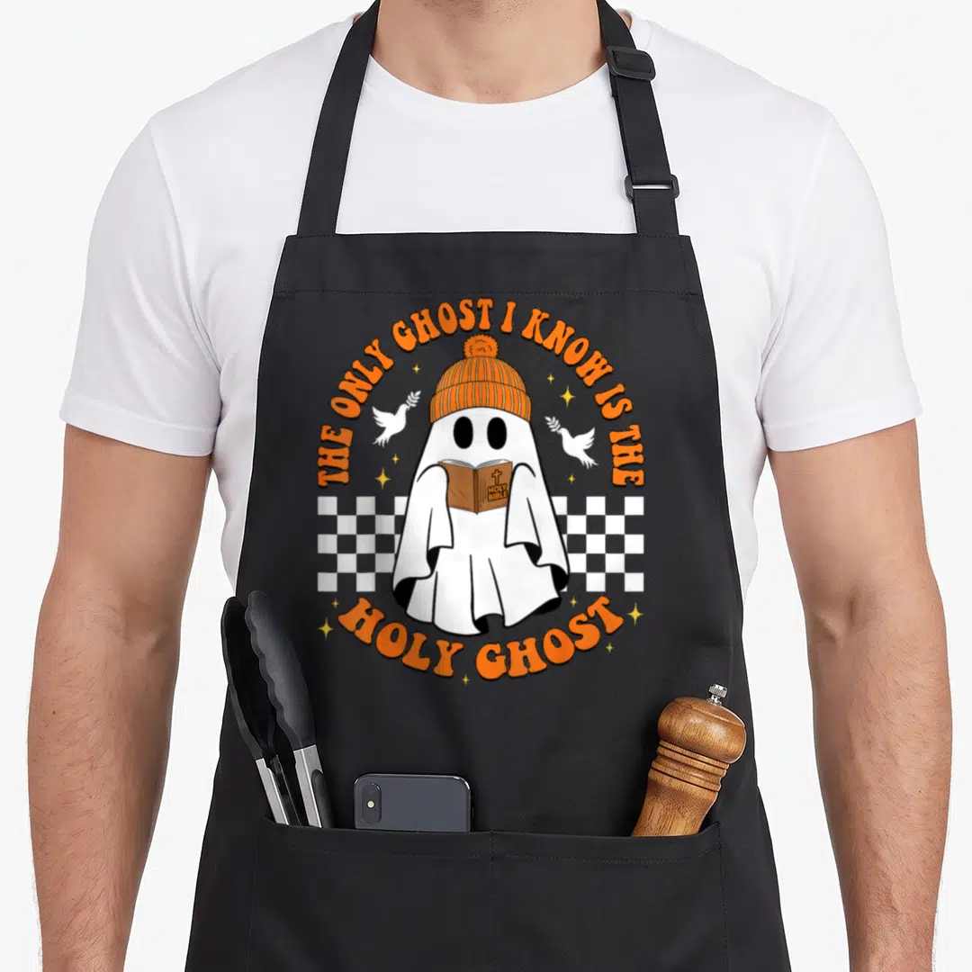 Holy halloween apron - Cartoon ghost in orange beanie holding Holy Bible book with doves and checkered background — shown on a black cotton canvas apron against a white background