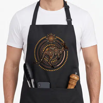 Dot kangaroo apron - Kangaroo silhouette filled with dots and concentric circles under a sun in brown orange white — shown on a black cotton canvas apron against a white background