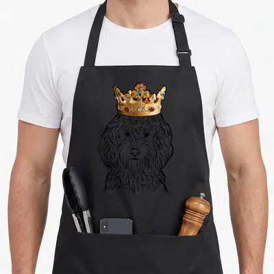 Crown cockapoo apron - Line art Cockapoo head wearing a jeweled gold crown — shown on a black cotton canvas apron against a white background
