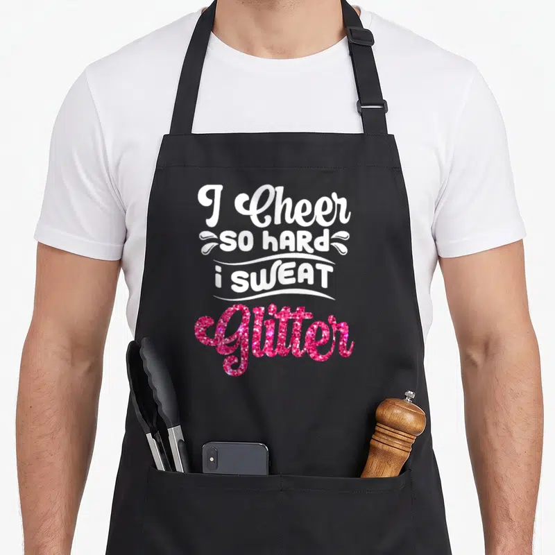 Funny cheer cheerleader cheerleading apron - I Cheer So Hard I Sweat Glitter text with white swirls and pink glitter — shown on a black cotton canvas apron against a white background