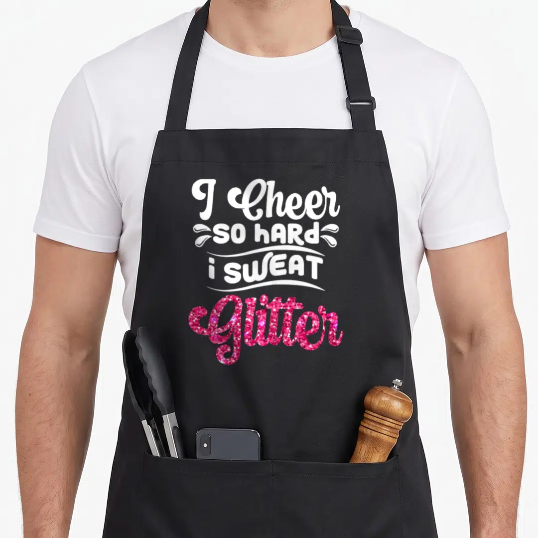 Funny cheer cheerleader cheerleading apron - I Cheer So Hard I Sweat Glitter text with white swirls and pink glitter — shown on a black cotton canvas apron against a white background