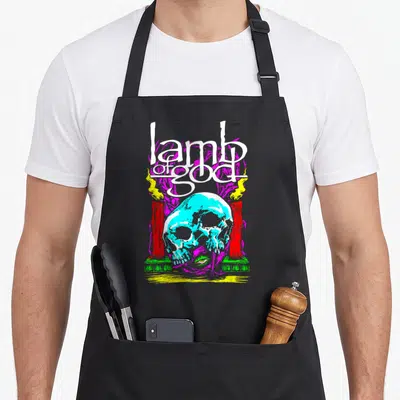 Lamb skull apron - Cyan skull, white stacked text, magenta background, yellow and red flames — shown on a black cotton canvas apron against a white background