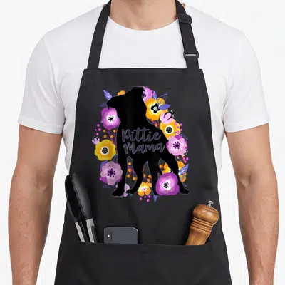 Mama flower dog apron - Black pit bull silhouette surrounded by purple pink yellow flowers with Pittie Mama text — shown on a black cotton canvas apron against a white background