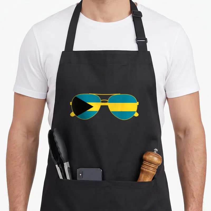 Sunglass bahamian apron - Minimalist aviator sunglasses with Bahamas flag pattern filling lenses in yellow blue — shown on a black cotton canvas apron against a white background