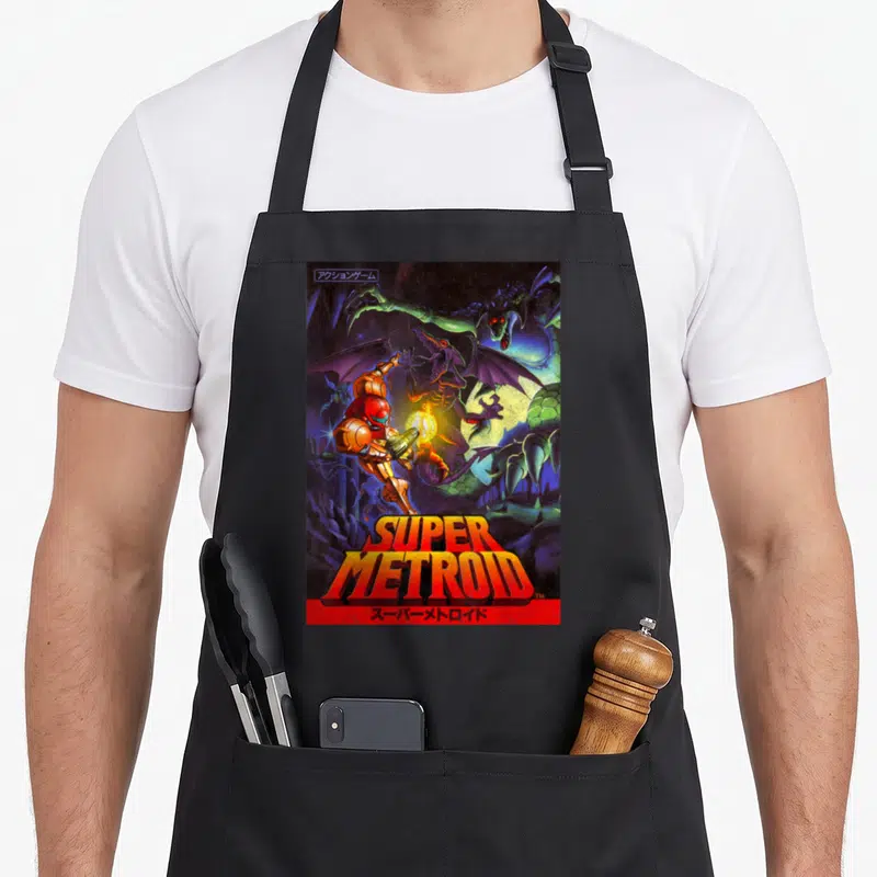 Samus metroidvania apron - Samus Aran facing monsters with Super Metroid title and Japanese text — shown on a black cotton canvas apron against a white background