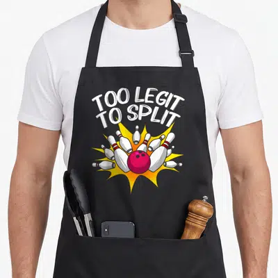Legit split apron - Pink bowling ball scattering white pins under arched TOO LEGIT TO SPLIT text on yellow burst — shown on a black cotton canvas apron against a white background