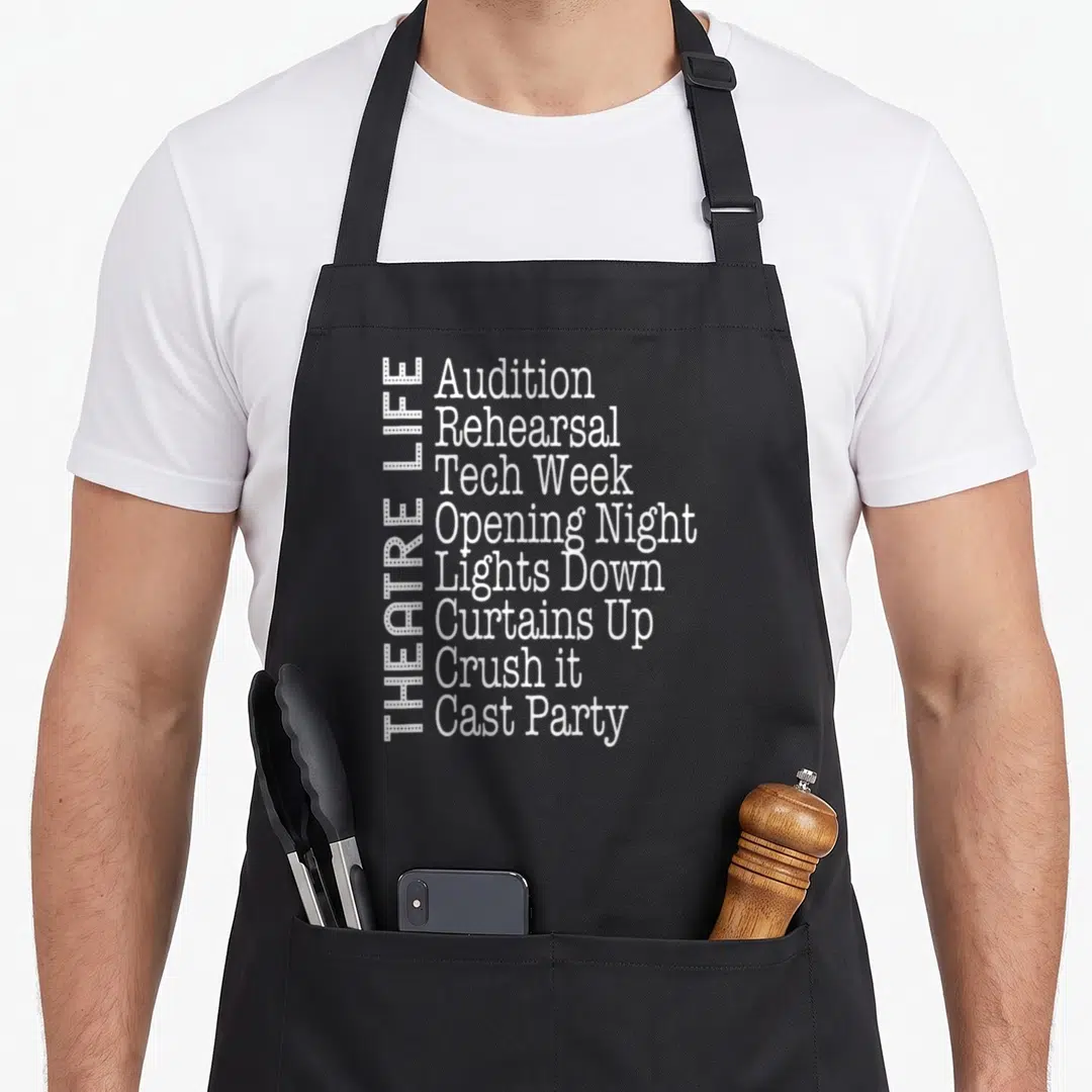 Broadway actor theatre apron - Vertical THEATRE LIFE text beside a list of eight production phrases in white font — shown on a black cotton canvas apron against a white background