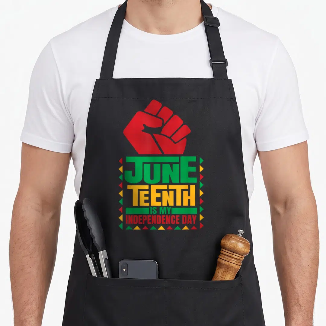 Juneteenth galveston apron - Red raised fist above stacked text JUNE TEENTH IS MY INDEPENDENCE DAY bordered by colored — shown on a black cotton canvas apron against a white background