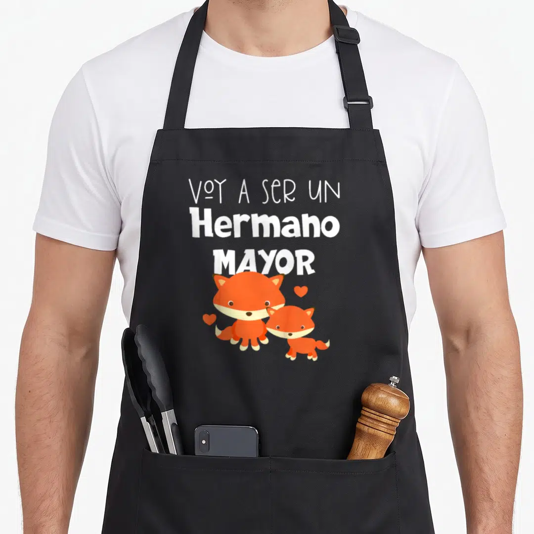 Voy spanish boy apron - VOY A SER UN Hermano MAYOR text with two orange foxes and three hearts — shown on a black cotton canvas apron against a white background