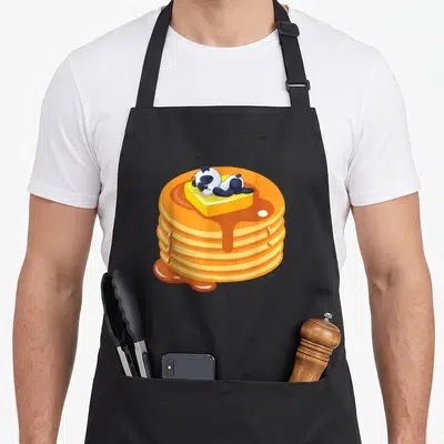 Baby pancake apron - Cartoon panda sleeping on butter atop five pancakes with dripping orange syrup — shown on a black cotton canvas apron against a white background