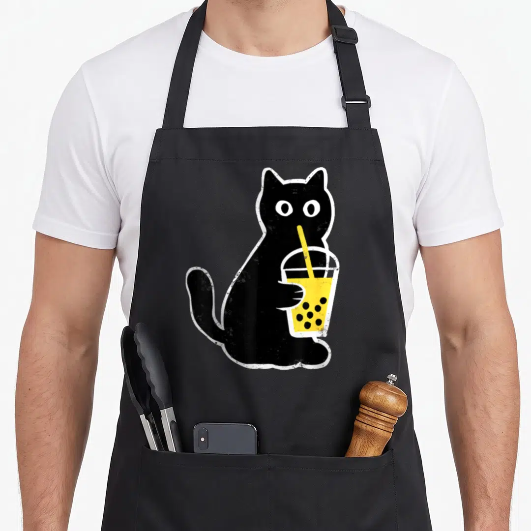 Boba anime cat apron - Distressed black cat illustration holding a yellow bubble tea cup with a straw and white border — shown on a black cotton canvas apron against a white background