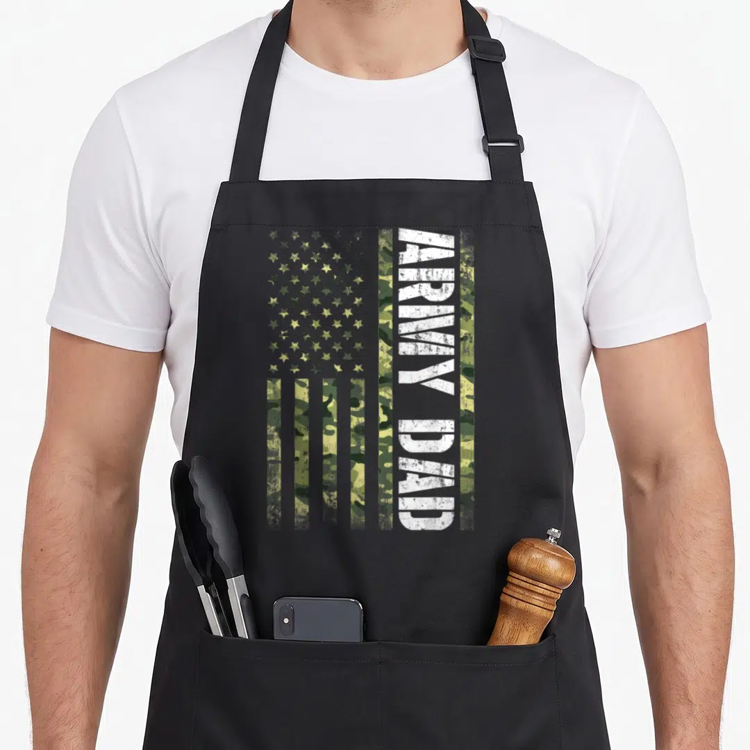 State father day apron - Vertical ARMY DAD text on camouflage US flag with distressed white lettering — shown on a black cotton canvas apron against a white background