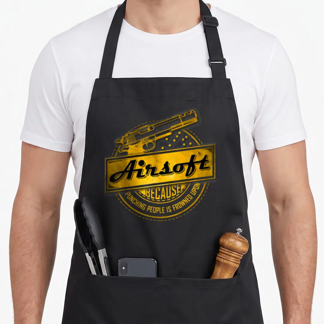 Punching airsoft apron - Yellow retro pistol graphic with Airsoft text and curved slogan on circular background — shown on a black cotton canvas apron against a white background