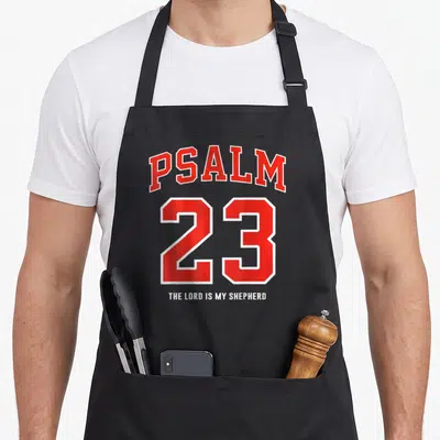 Lord shepherd psalm apron - Red and white PSALM 23 THE LORD IS MY SHEPHERD typography on grey background — shown on a black cotton canvas apron against a white background