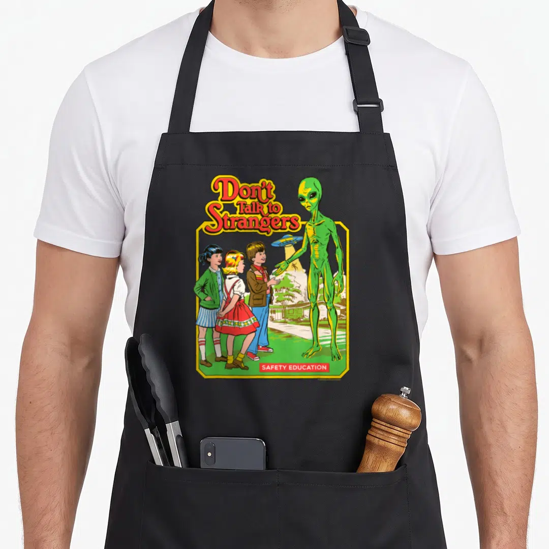 Steven funny alien apron - Retro Don't Talk to Strangers alien illustration with three children and yellow border — shown on a black cotton canvas apron against a white background