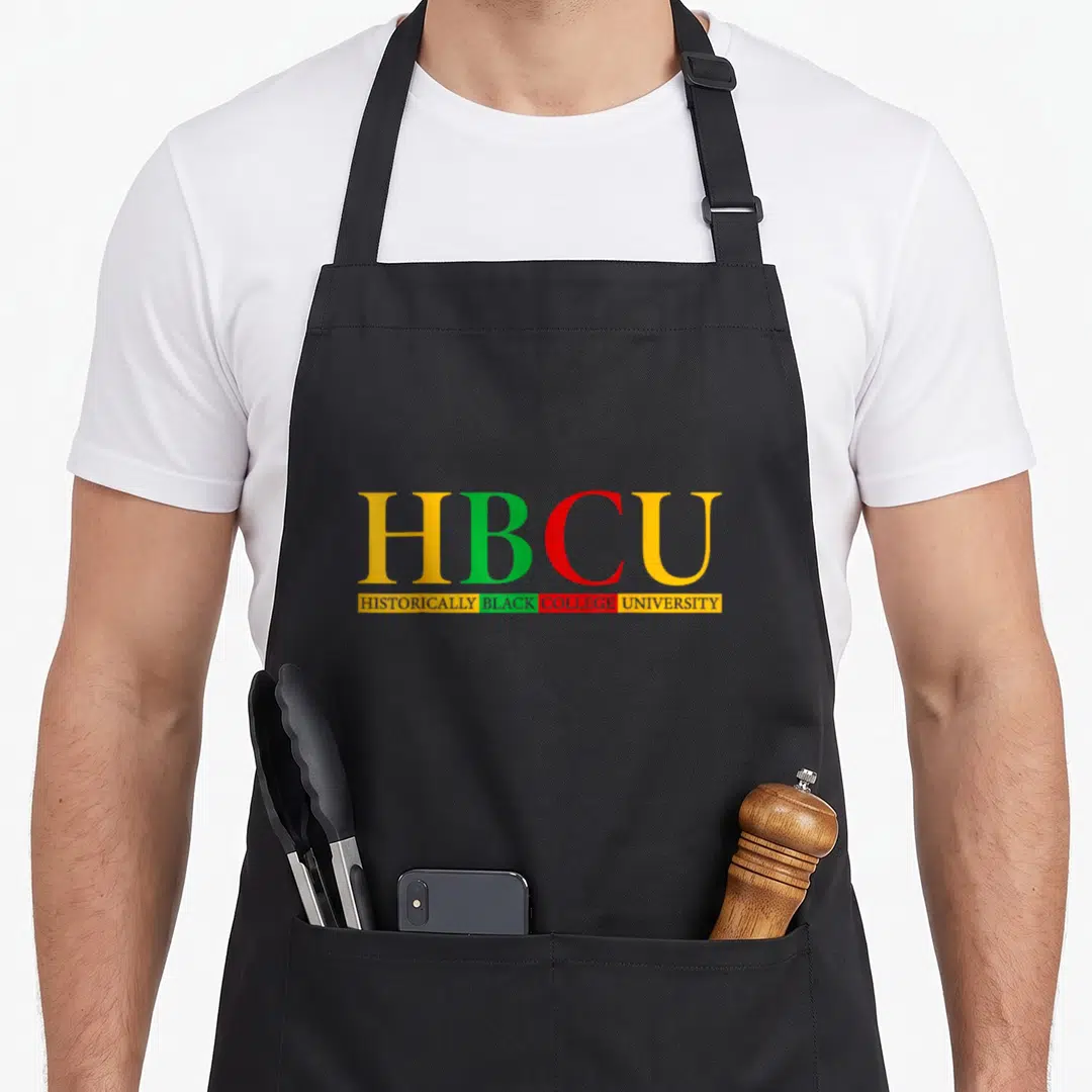 Graduate historical aprons - HBCU acronym in yellow green red with HISTORICALLY BLACK COLLEGE UNIVERSITY text below — shown on a black cotton canvas apron against a white background