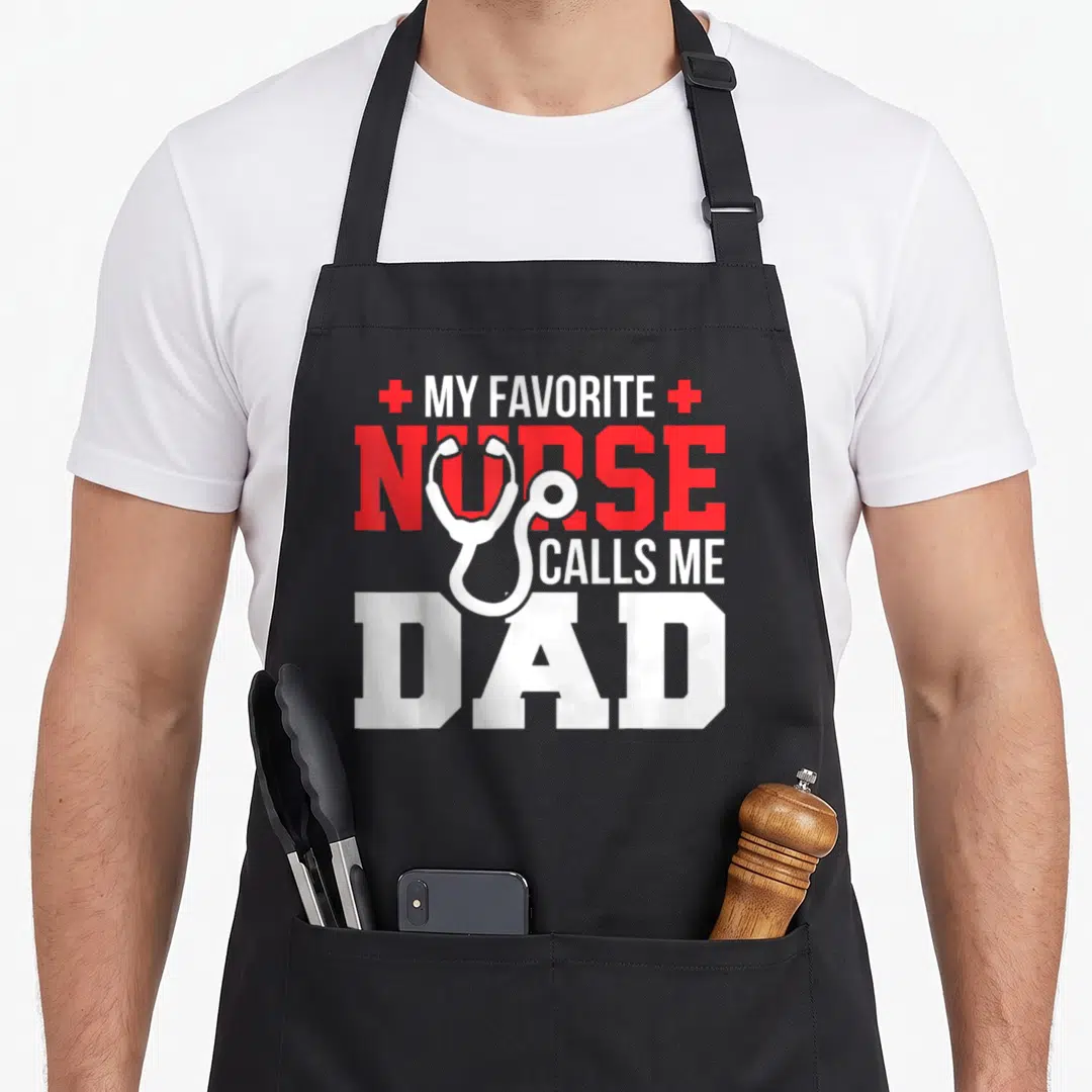 Call father nurses apron - White stethoscope over red and white text MY FAVORITE NURSE CALLS ME DAD flanked by two red — shown on a black cotton canvas apron against a white background