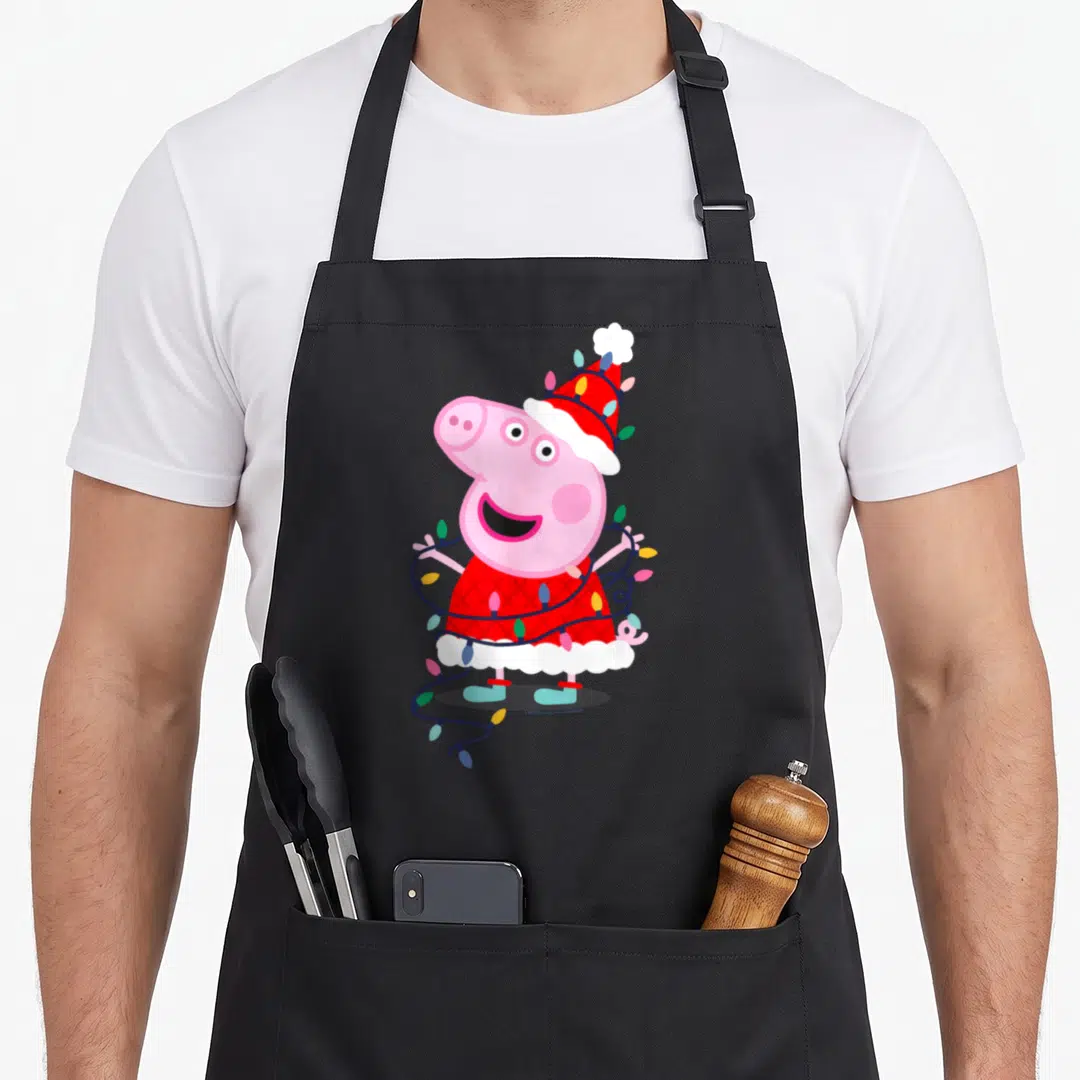 Cool christmas lights apron - Peppa Pig in red Santa dress wrapped in colorful Christmas lights wearing teal boots — shown on a black cotton canvas apron against a white background