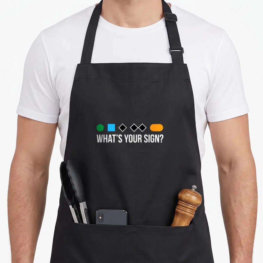 Ski apron or apron - Five colored geometric shapes above white text reading WHAT'S YOUR SIGN? — shown on a black cotton canvas apron against a white background