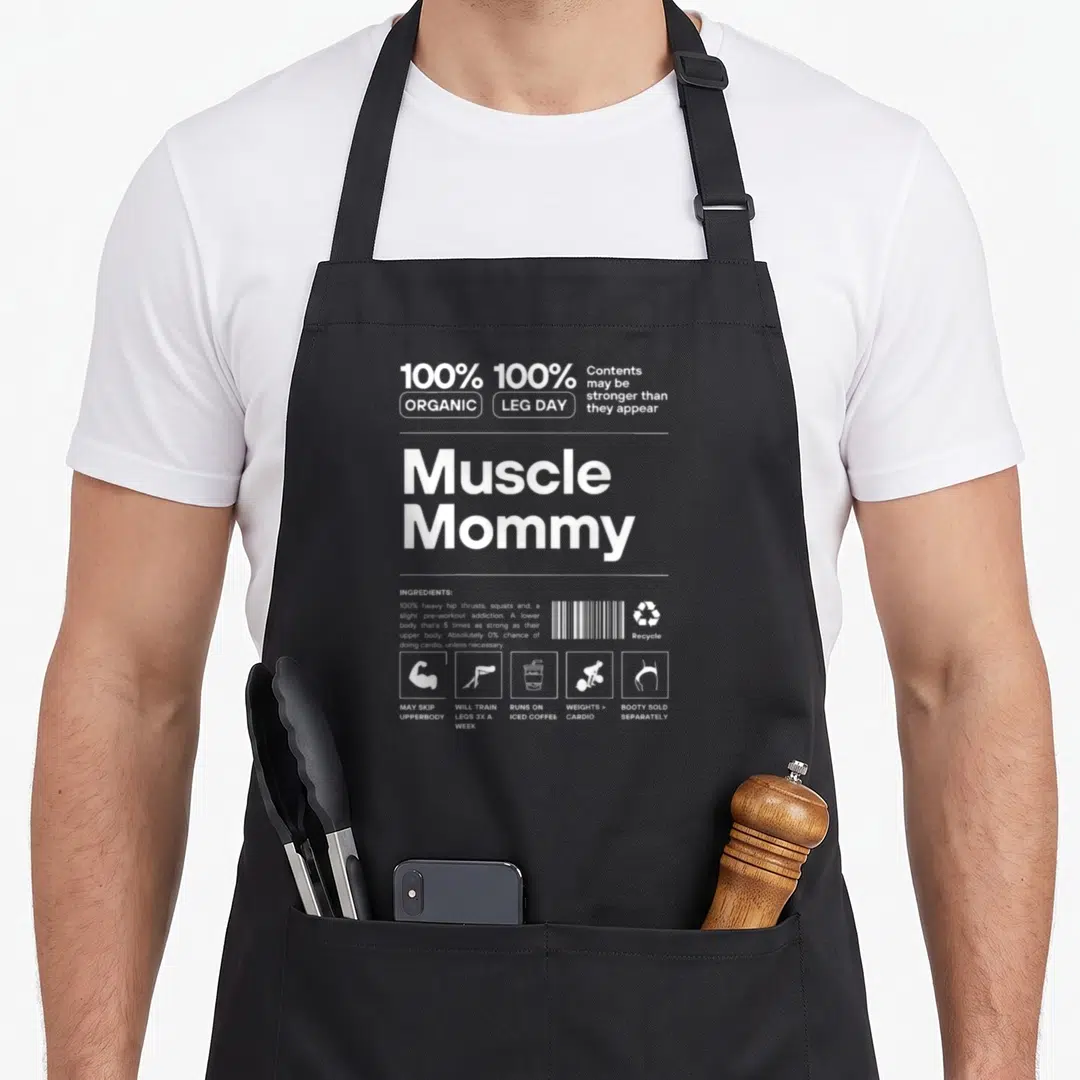 Bodybuilding muscle apron - White nutrition label graphic reading Muscle Mommy with gym icons and ingredient list — shown on a black cotton canvas apron against a white background