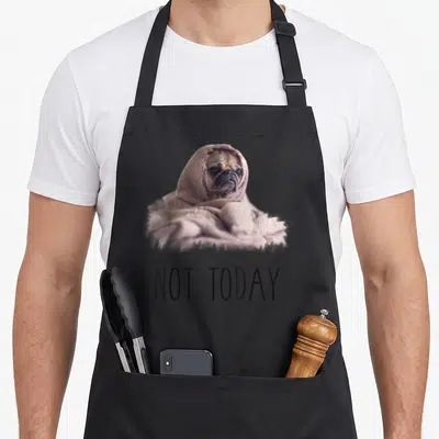 Blanket dog apron - Pug in beige blanket above NOT TODAY text on grey background — shown on a black cotton canvas apron against a white background