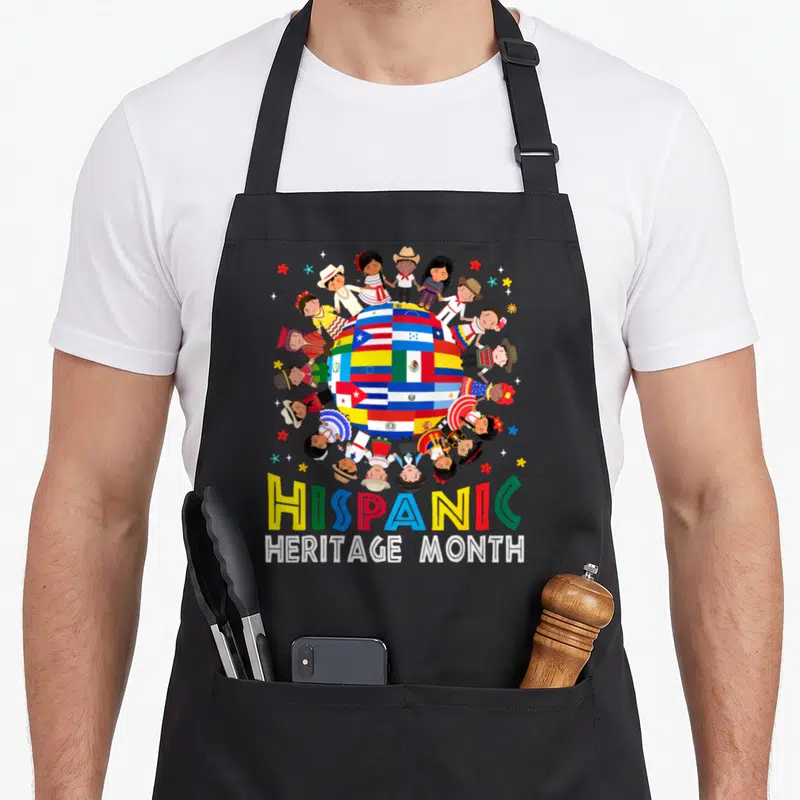 Month hispanic apron - Cartoon globe of flags surrounded by children in traditional dress with multicolored HISPANIC — shown on a black cotton canvas apron against a white background