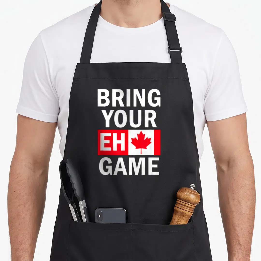 Bring canadian aprons - Stacked BRING YOUR EH GAME text with red maple leaf in white center panel — shown on a black cotton canvas apron against a white background