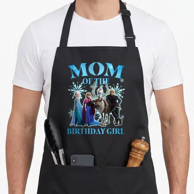 Frozen birthday apron - Mom of the Birthday Girl text with Frozen characters and blue snowflakes — shown on a black cotton canvas apron against a white background