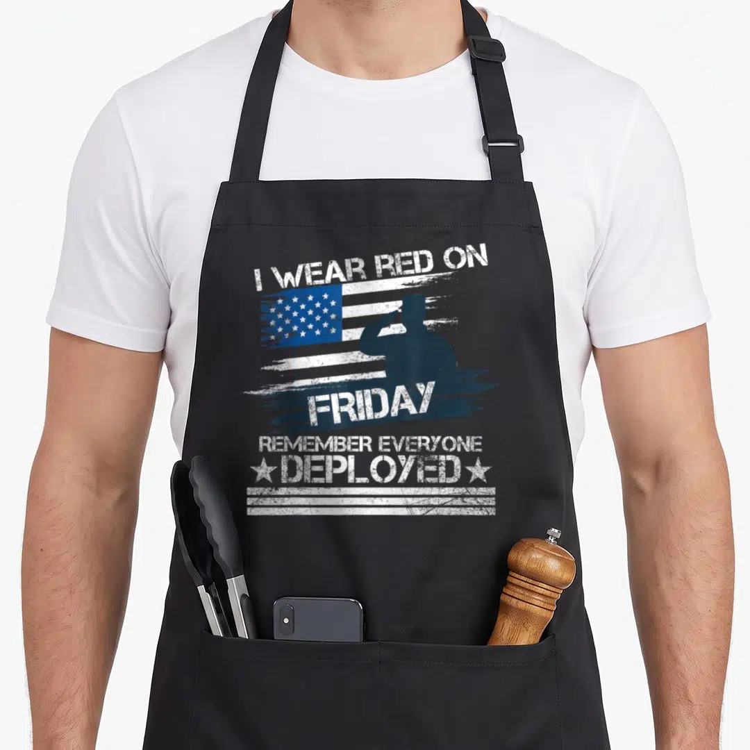 Friday military apron - Saluting soldier silhouette over distressed flag with text I wear red on Friday remember — shown on a black cotton canvas apron against a white background